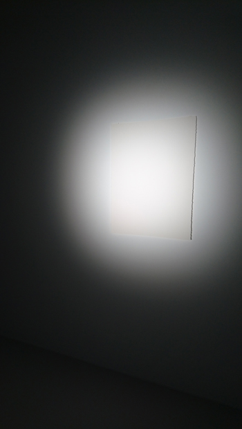 《crossfades –Torch–》（2020年）強力な照明に照らされた壁面に掲示されてある紙。よく見ようと近寄ると自身の影が紙の上に重なる。すると今まで見えていなかった何かが見えるようになる。