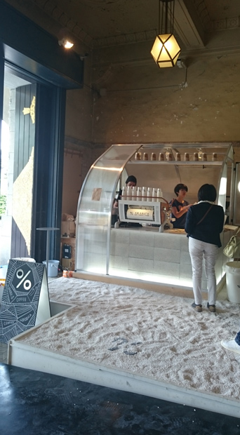 「PARASOPHIA : 京都国際現代芸術祭 2015」開催時、東玄関には名和晃平＆SANDWICHが設計したエントランスサインが設置されたカフェができた。足元はカフェ部分だけ段差を補整した砂場にしてあったが、今回の改修ではこの段差（300mm）を広間全体で解消した。（「PARASOPHIA : 京都国際現代芸術祭 2015」開催時に撮影）