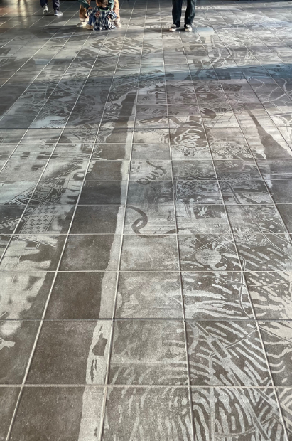 SIDE COREによる《Patchwork my city》（2023年）は、THEATER MILANO-Zaのホワイエの床タイルsを削って描かれた大作。大きな手のひらの中に東京の地図やドローイングがコラージュされている。