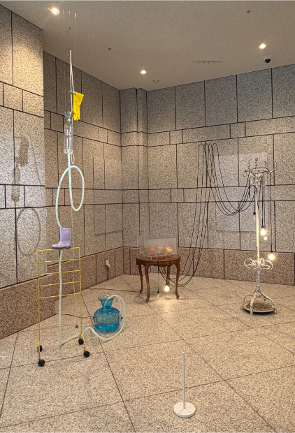 「毛利悠子 Recompose」展示風景　結界にカラフルなゴムが使われているところや、配線モールが光沢のある金色のものが使用されているなど、通常、余計なものとして扱われがちなものが、この場所の環境の要素として展示に取り込まれている。